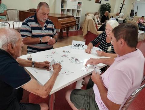 Prijímatelia sociálnej služby z DSS Zavar pri kartovej hre v ZpS Trnava Vansova. 