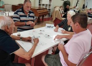 Prijímatelia sociálnej služby z DSS Zavar pri kartovej hre v ZpS Trnava Vansova. 
